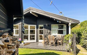 Ein Holzhaus mit Veranda, großen Fenstern und Gartenmöbeln.