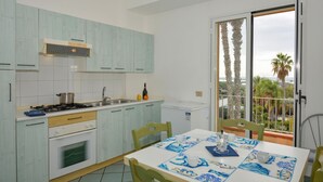 Une cuisine avec des meubles de couleur bleu clair, une cuisinière, un évier et une table recouverte d’une nappe bleue et blanche.
