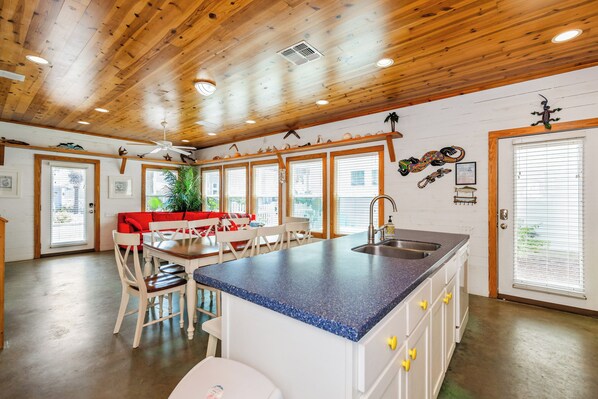 A kitchen with a blue countertop, white cabinets, and a wooden ceiling.