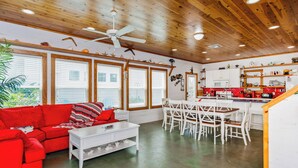 A spacious living area with a red sofa, white coffee table, and dining set. - Seashell Escape--3 BR House in Village Walk, Sleeps 10, Near Beach, Dogs OK! (Port Aransas)