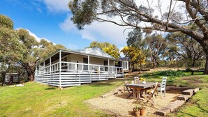 A white wooden house with a porch, surrounded by a grassy yard and trees. - Havana Villa MALDON (Maldon)