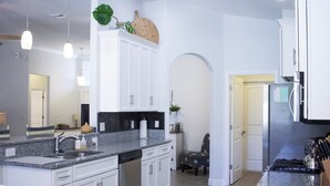 A modern kitchen with white cabinetry, granite countertops, and stainless steel appliances. - Hibiscus Hideaway in Cocoa Beach (Cocoa Beach)