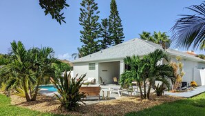 A house with a pool, surrounded by palm trees and a well-maintained lawn. - Hibiscus Hideaway in Cocoa Beach (Cocoa Beach)