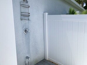 A white exterior wall with a metal door and a white fence. - Hibiscus Hideaway: Pool, Spa & Steps to the beach (Cocoa Beach)