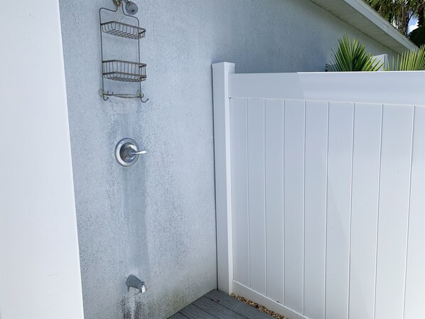 A white exterior wall with a metal door and a white fence. - Hibiscus Hideaway: Pool, Spa & Steps to the beach (Cocoa Beach)