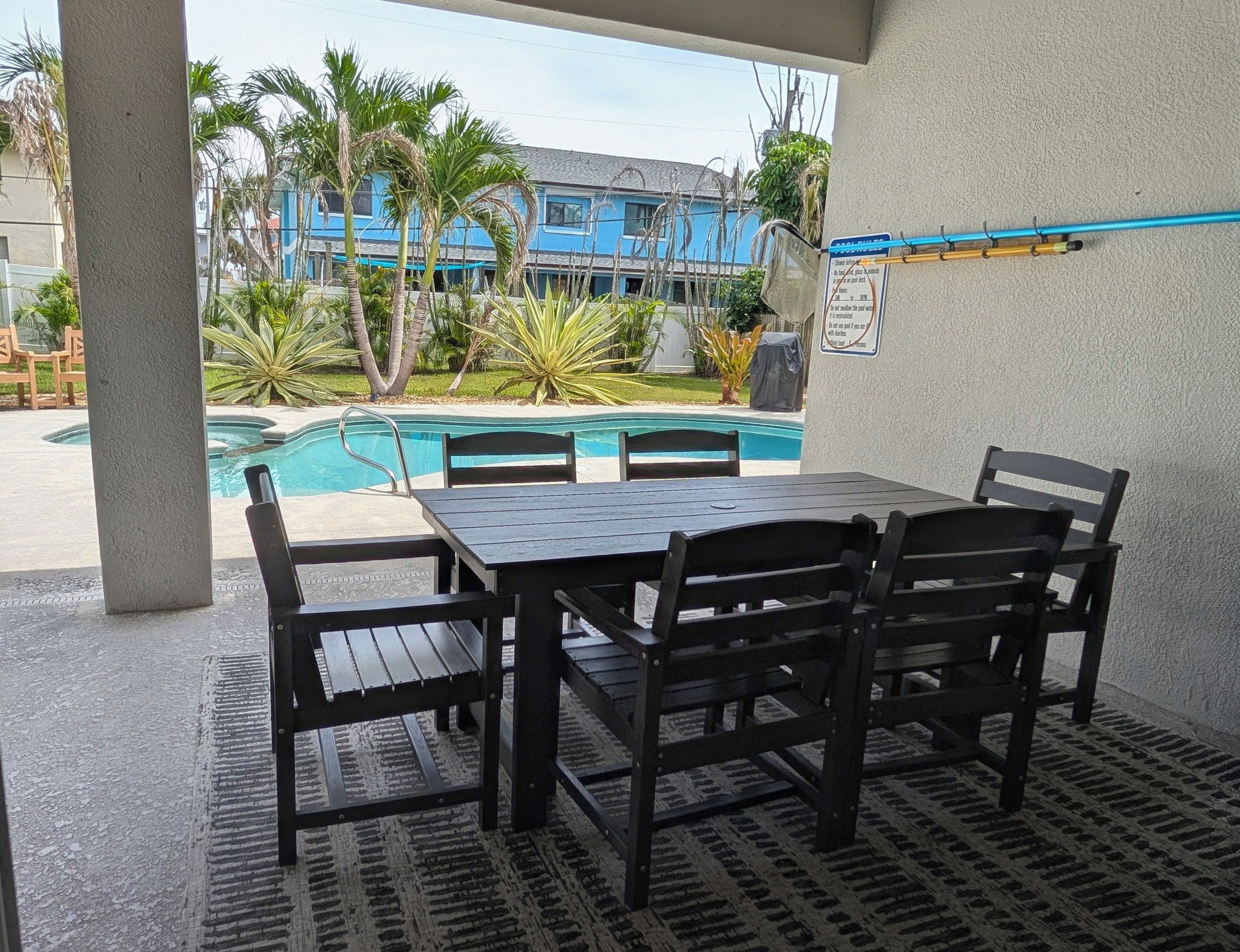 An outdoor patio with a pool, a table, and chairs.