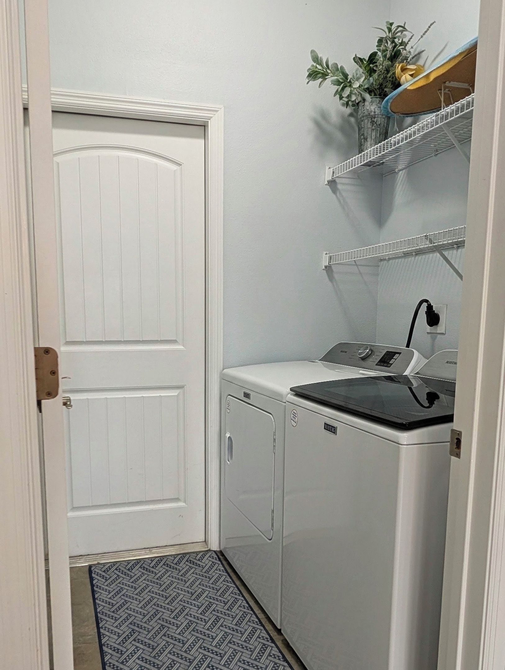 Een wasserette met een witte deur, een wasmachine en een wastafel met kraan.