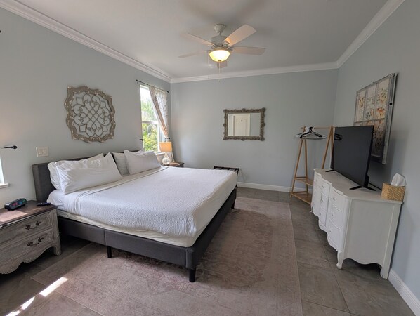 A bedroom with a bed, bedside tables, a dresser, a television, and a ceiling fan.