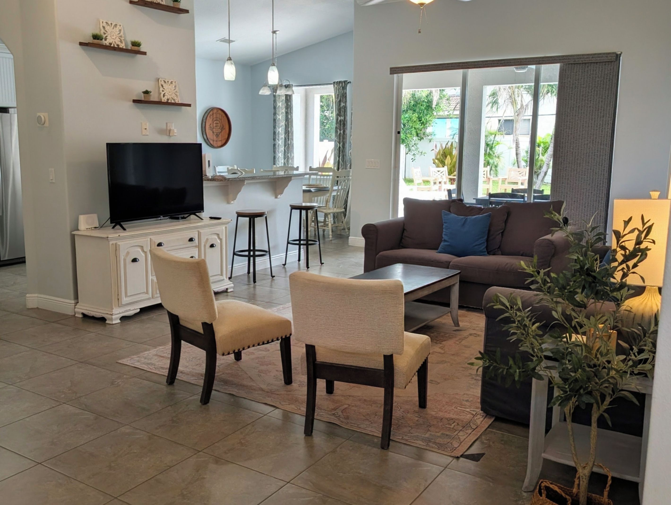 Una sala de estar con televisor, asientos, una mesa de centro y vistas al exterior.