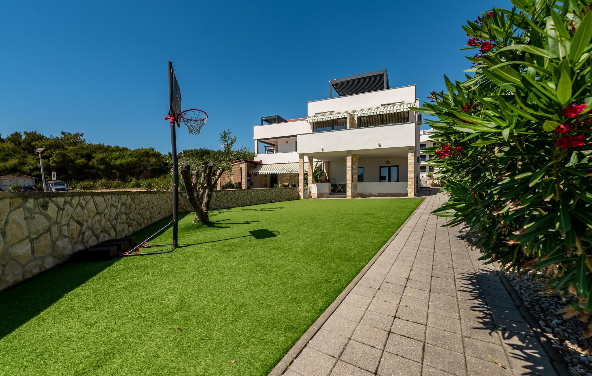 Uma casa moderna de dois andares com gramado bem cuidado e um aro de basquete.