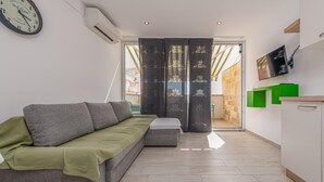Ein modernes Wohnzimmer mit einem grauen Sofa, einem kleinen Tisch und einem an der Wand befestigten Fernseher.