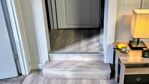Un escalier avec des marches recouvertes de bois menant à une pièce dont la porte est blanche.