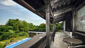 Ein Balkon mit Pool, Sitzgelegenheit im Freien und Blick auf einen üppigen Garten.