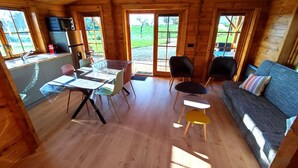 Een gezellig chaletinterieur met een eethoek, een bank en een keuken.