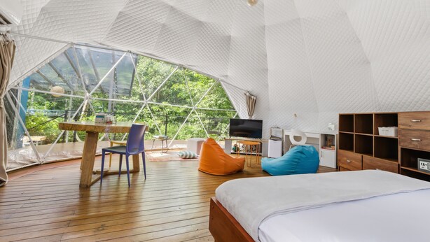 A spacious room with a large bed, a wooden table, a TV, and a view through a large window.