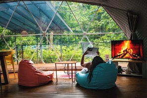 A cozy room with a large window, a television, and a wooden floor.