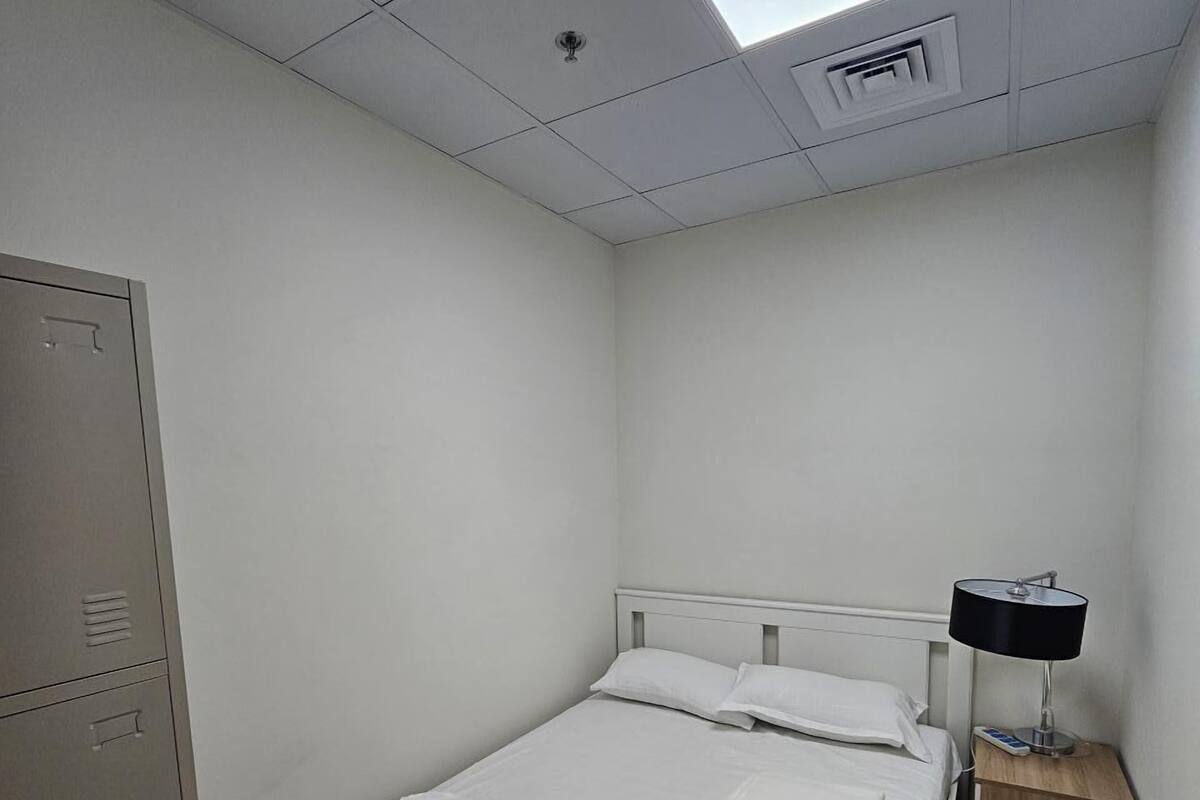 A single-bed room with a skylight, a bedside table with a lamp, and a wardrobe.