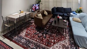 A modern living room with a dining area, a sofa, a coffee table, and a TV. - Khalifa Holiday's  (Dubai)