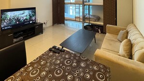 A modern living room with a flat-screen TV, a sofa, a patterned ottoman, and a view of a cityscape through large windows. - Khalifa Holiday's  (Dubai)