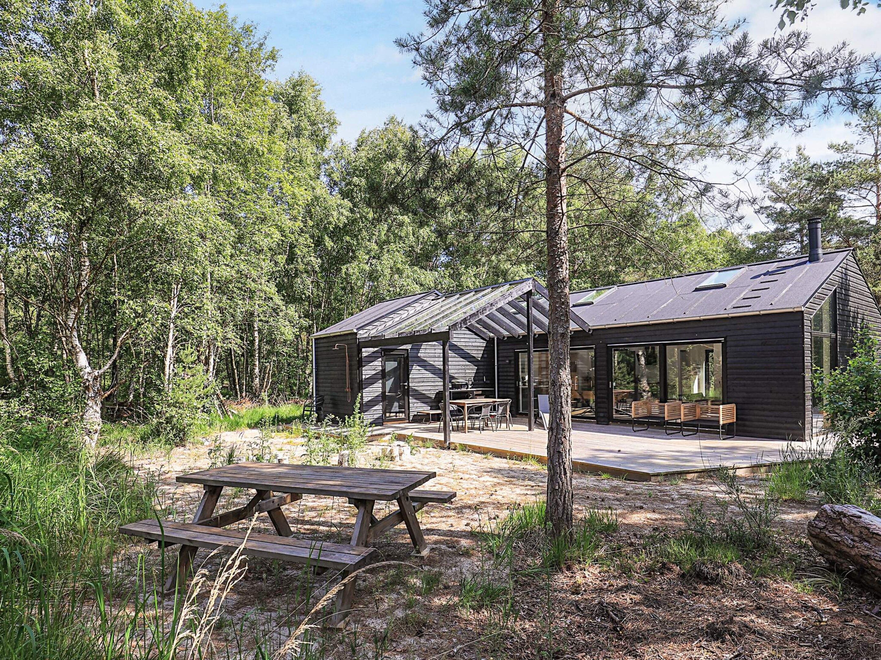 A cabin with a covered patio, a dining area, and a large window.