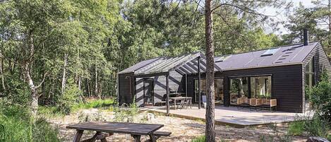 A cabin with a covered patio, a dining area, and a large window.
