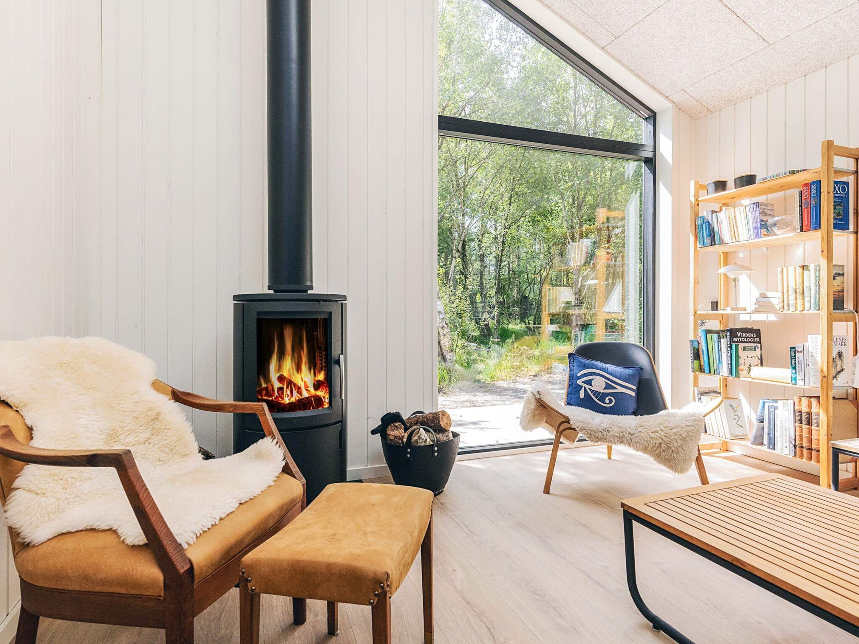 A cozy room with a wood-burning stove, a leather chair, a wooden bench, and a bookshelf filled with books.