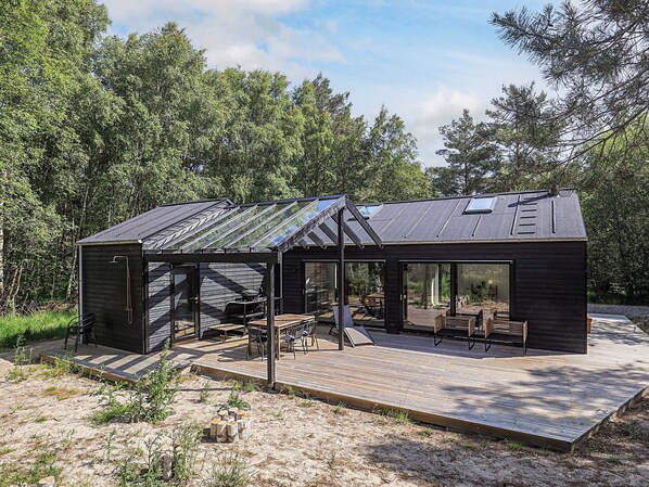 Een moderne cabin met een ruim terras, ingebouwde zitplaatsen en een glazen omheining.