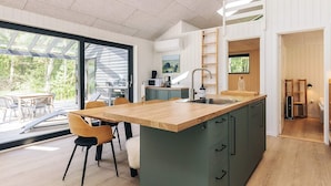 Cozinha moderna com uma ilha grande, soalho de madeira e vista para o exterior.