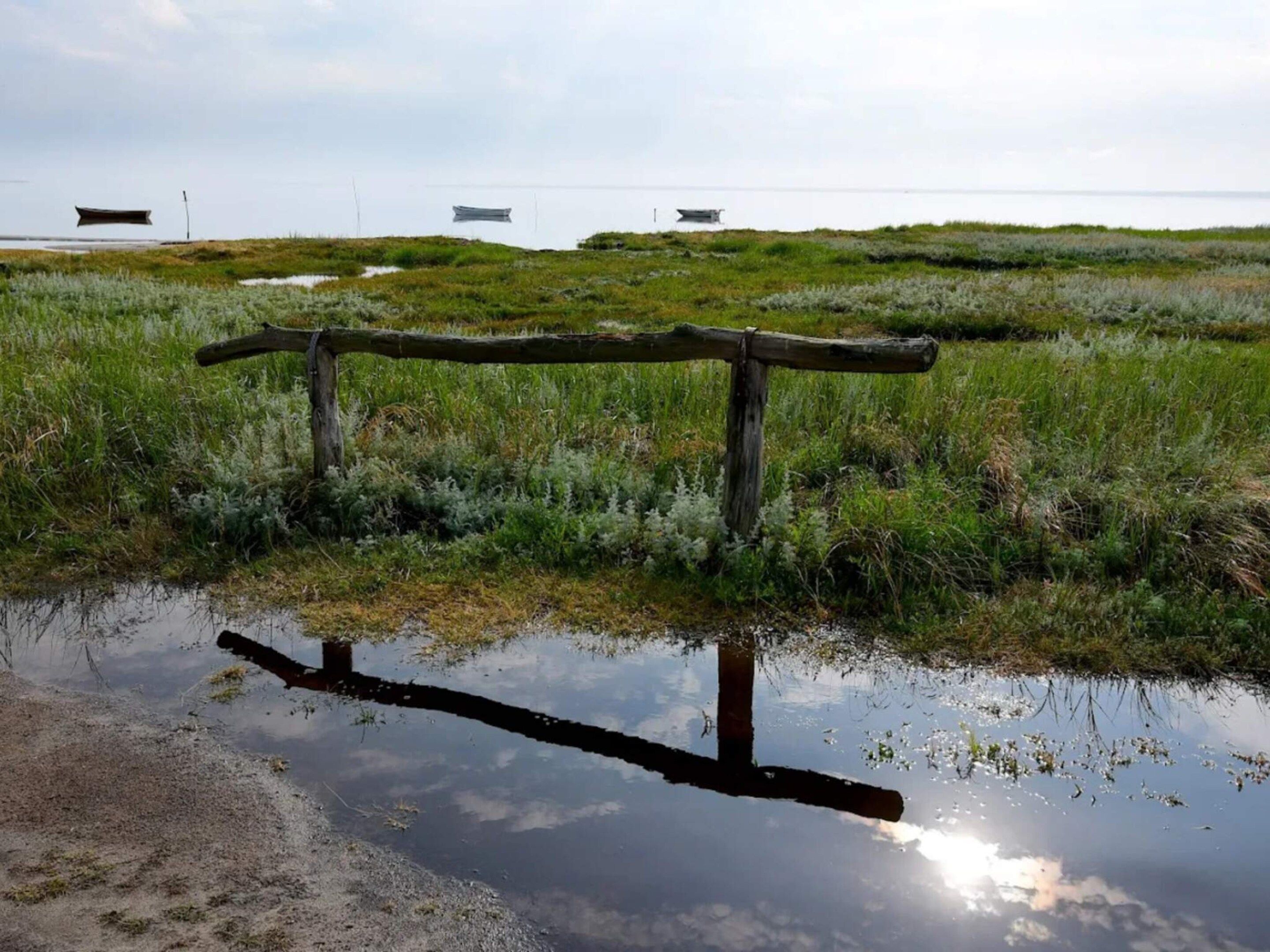 A wooden fence in a natural landscape with a body of water in the foreground.