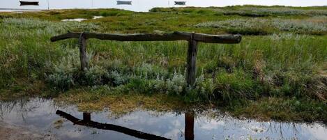 A wooden fence in a natural landscape with a body of water in the foreground.
