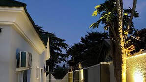 A narrow pathway leading to a white building with multiple windows and a tiled entrance. - BA2 Homes (Abuja)