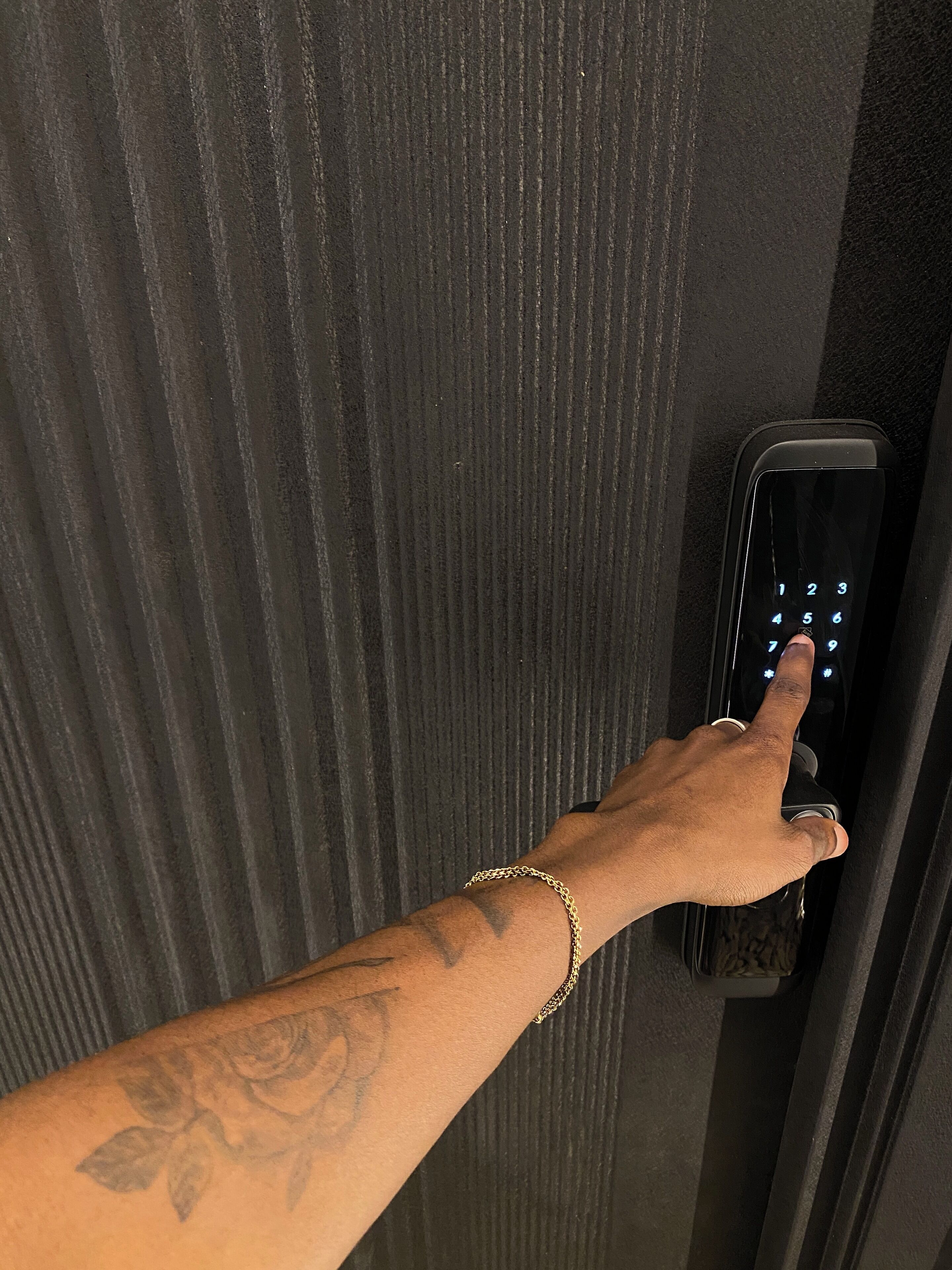 A hand pressing a numeric keypad on a door lock.