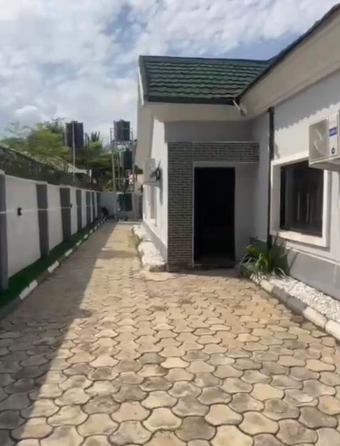 A paved pathway leading to a building with a green roof and a white exterior.