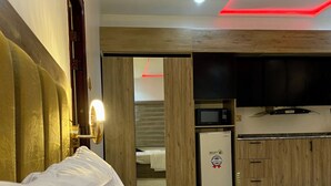 A hotel room with a bed, a desk, a microwave, and a TV. - BA2 Homes (Abuja)