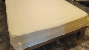Uma cama bem arrumada com travesseiros e cobertor, um abajur e uma parede com um quadro.