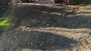 Uma casa com varanda coberta, um carro estacionado na frente e um muro de pedra.