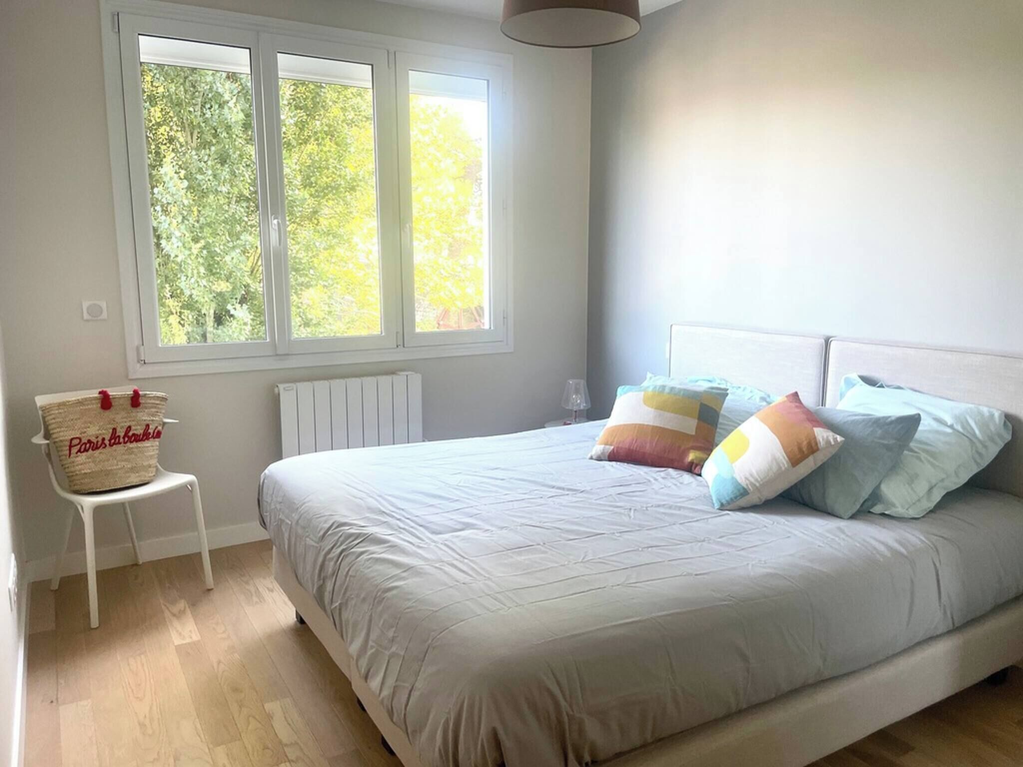 Ein Schlafzimmer mit Bett, Fenster, Stuhl und Heizkörper.