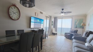 Un salón amplio con zona de comedor, un televisor de pantalla plana grande y un balcón con vistas.