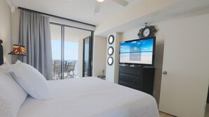 Habitación de hotel con una cama grande, televisión, balcón con vistas y una puerta.