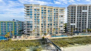 Un hotel frente a la playa con varios balcones, piscina y acceso a la playa.