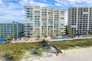 A beachfront hotel with multiple balconies, a pool, and a beach access walkway.