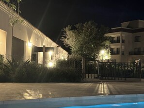 A nighttime view of a building with a gated entrance, a pool, and surrounding greenery. - Alpine View Chalet (Cafayate)