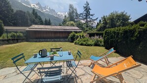 An outdoor seating area with a table and chairs, a water bottle, and a kettle. - Appartement Sérénité - Welkeys (Chamonix-Mont-Blanc)