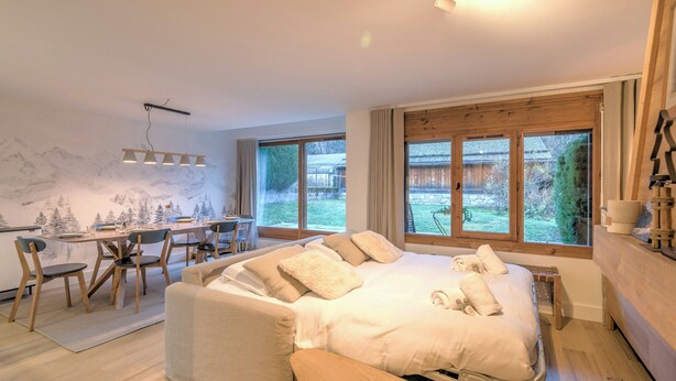 A modern bedroom with a large bed, a desk, and a view of the outdoors. - Appartement Sérénité - Welkeys (Chamonix-Mont-Blanc)