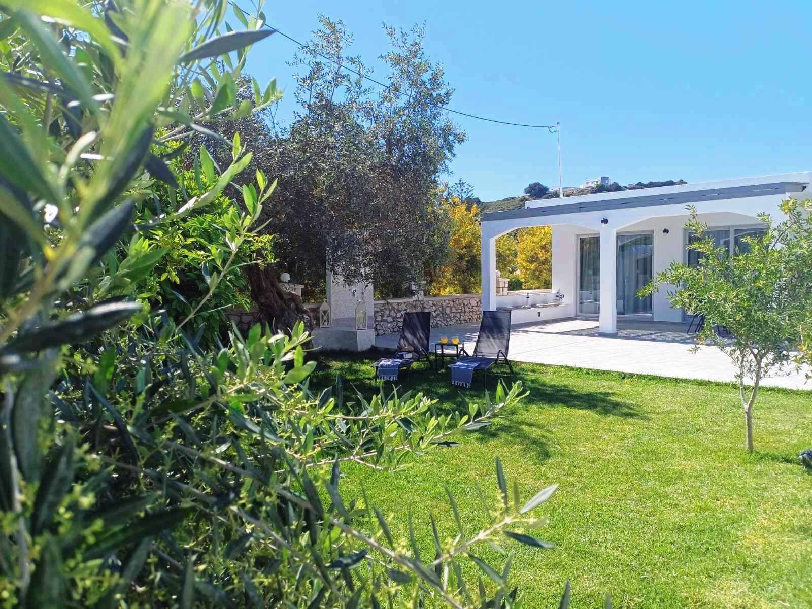Una casa moderna con patio, un muro in pietra e un prato.