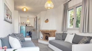 Una sala de estar moderna con un conjunto de sofás, una chimenea y una cocina al fondo.