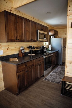 Une cuisine dotée de meubles en bois, d’appareils électroménagers en acier inoxydable et d’un plan de travail en granit.