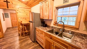 A kitchen with wooden cabinets, a granite countertop, a stainless steel sink, and a refrigerator.