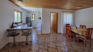 Une cuisine dotée d’un îlot central, de deux tabourets de bar, d’une table à manger avec des chaises et d’un plafond en bois.