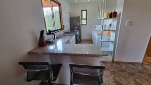 Une cuisine compacte dotée d’un plan de travail en granit, de deux tabourets de bar, d’un réfrigérateur et d’un four à micro-ondes.